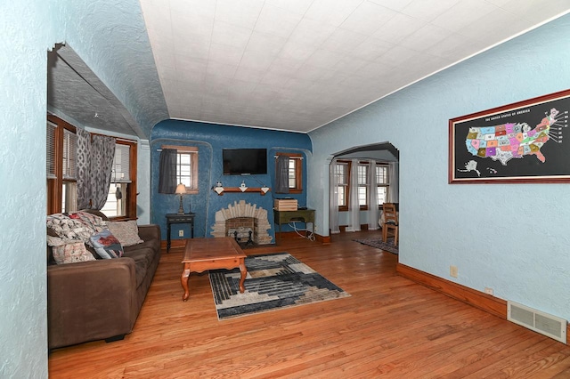 living room featuring hardwood / wood-style floors, a stone fireplace, and plenty of natural light