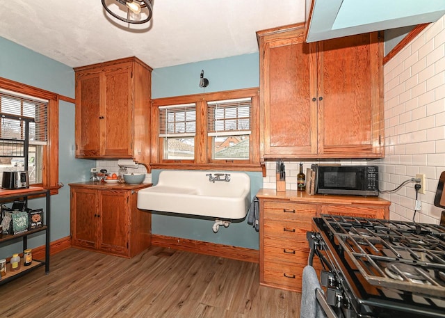 kitchen with gas stove, light hardwood / wood-style floors, sink, and decorative backsplash