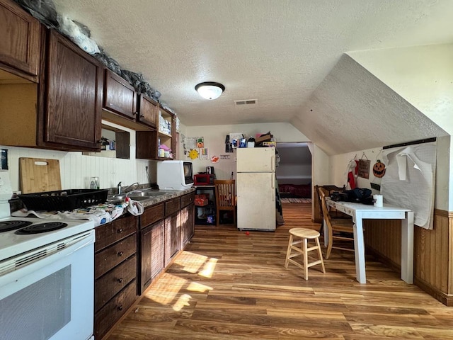 kitchen with dark brown cabinetry, sink, a textured ceiling, hardwood / wood-style flooring, and white appliances