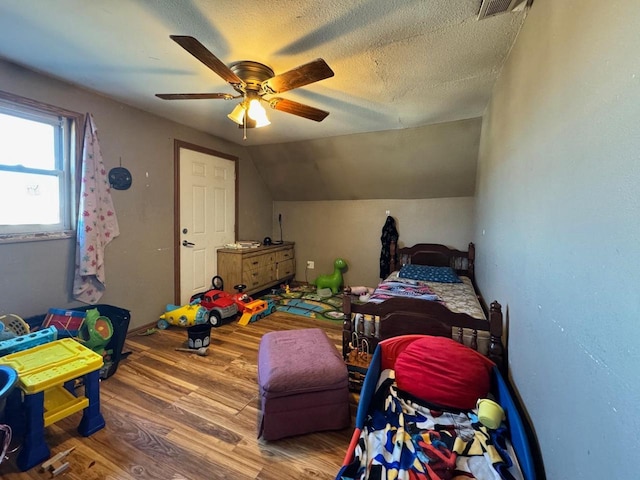 bedroom featuring ceiling fan, vaulted ceiling, hardwood / wood-style floors, and a textured ceiling