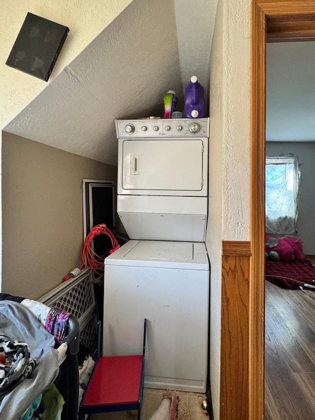 clothes washing area featuring dark hardwood / wood-style flooring, stacked washer / drying machine, and a textured ceiling