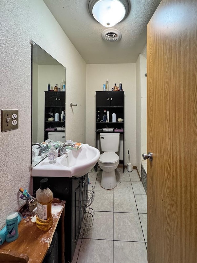 bathroom with tile patterned flooring, vanity, a textured ceiling, and toilet