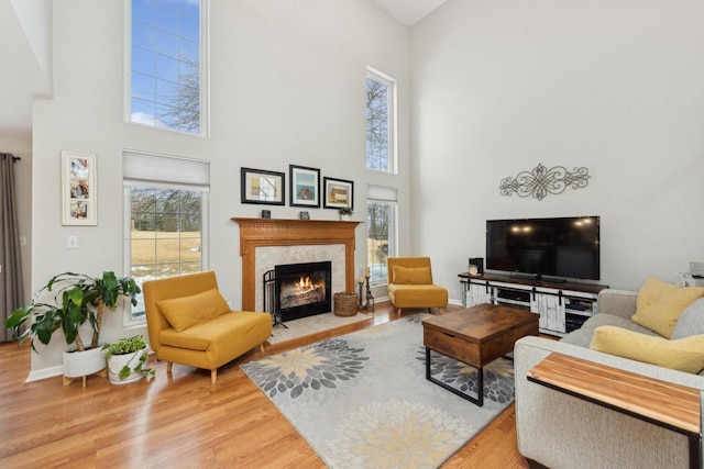 living room with a towering ceiling, hardwood / wood-style floors, and a high end fireplace