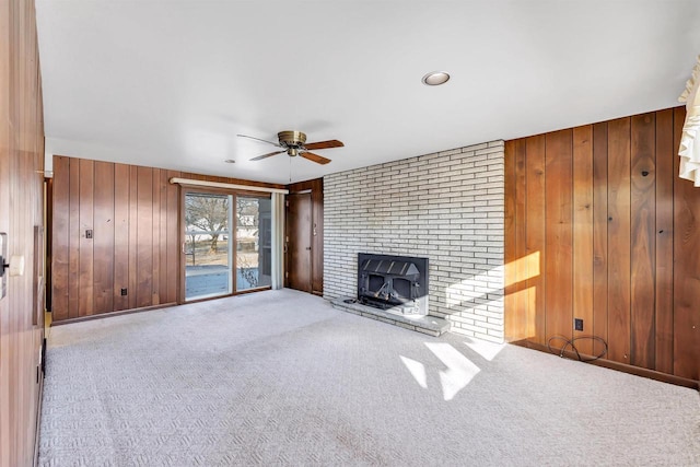 unfurnished living room featuring ceiling fan, light colored carpet, and wood walls