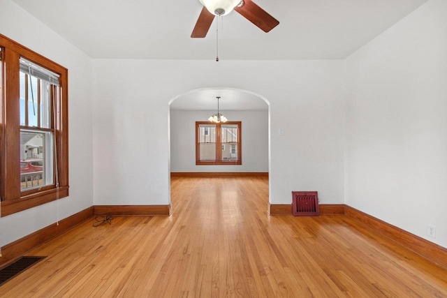 unfurnished room featuring ceiling fan with notable chandelier and light hardwood / wood-style floors