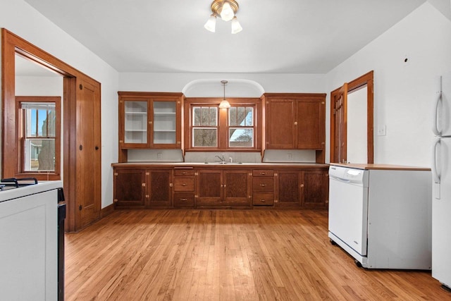 kitchen featuring sink, hanging light fixtures, light wood-type flooring, dishwasher, and stove