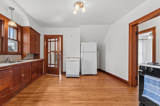 kitchen featuring sink, pendant lighting, white appliances, and light hardwood / wood-style floors