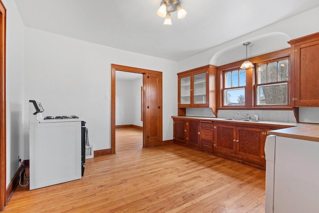 kitchen with white gas range, sink, pendant lighting, and light hardwood / wood-style floors