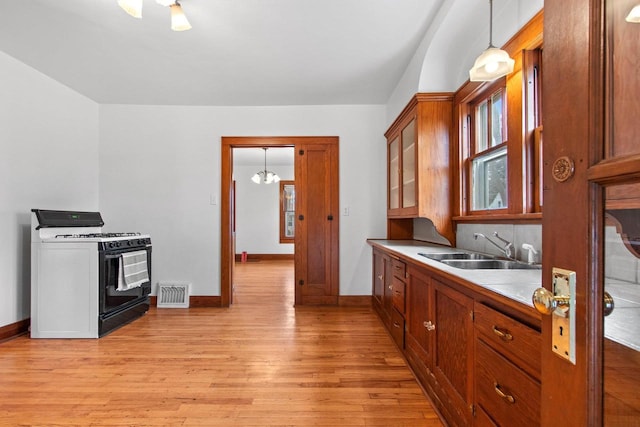 kitchen featuring decorative light fixtures, sink, range with gas cooktop, and light hardwood / wood-style floors