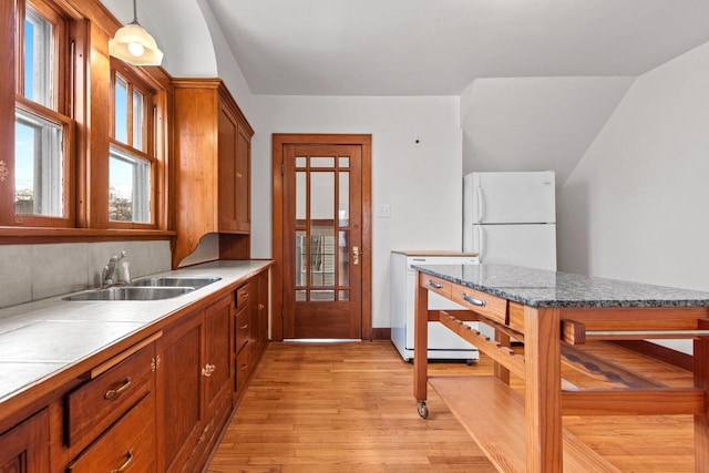 kitchen featuring sink, decorative light fixtures, white appliances, light hardwood / wood-style floors, and decorative backsplash