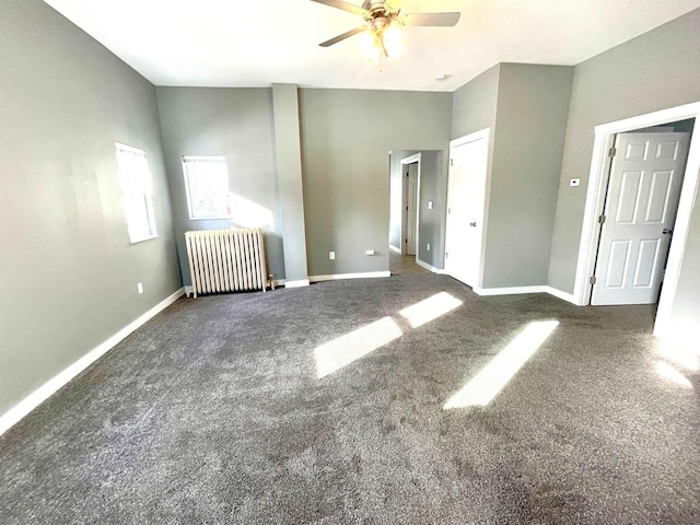 unfurnished bedroom with dark carpet, radiator heating unit, and ceiling fan