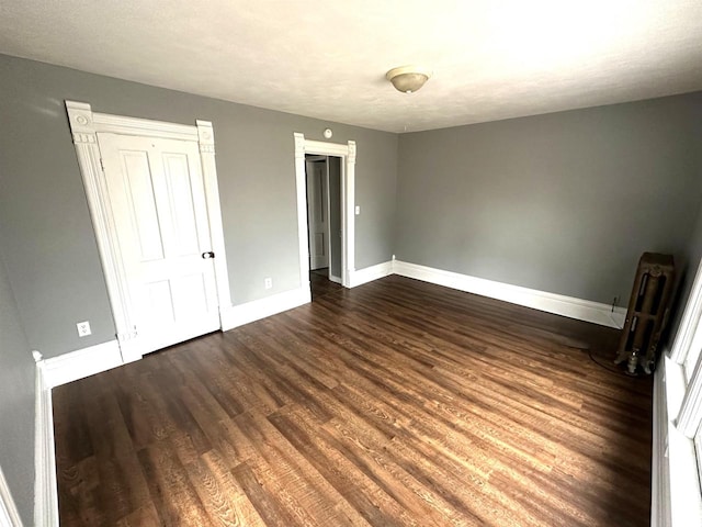 unfurnished bedroom with radiator, dark wood-type flooring, and a textured ceiling