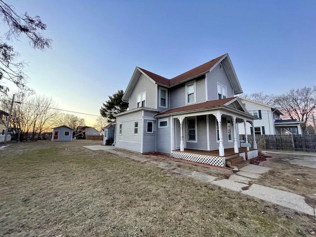 property exterior at dusk featuring a yard and covered porch