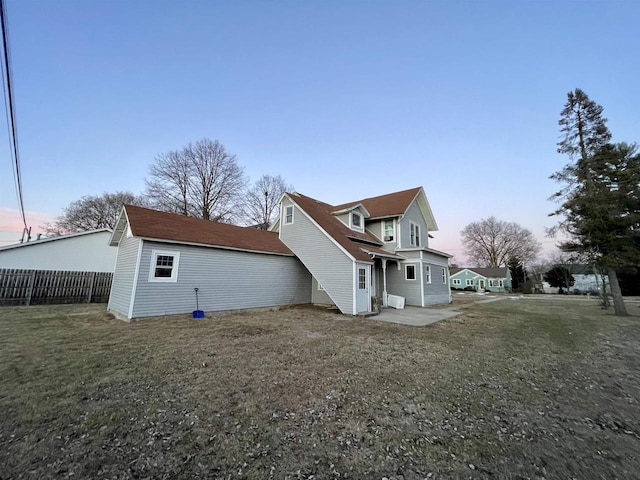 back house at dusk featuring a yard and a patio area