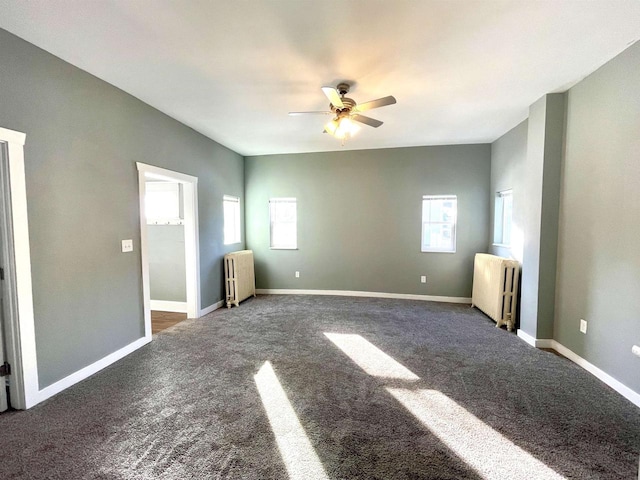 unfurnished living room featuring dark colored carpet, plenty of natural light, and radiator heating unit