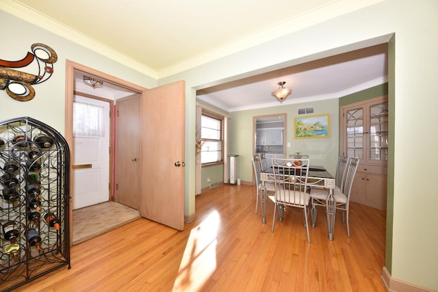 dining room with ornamental molding and light hardwood / wood-style flooring