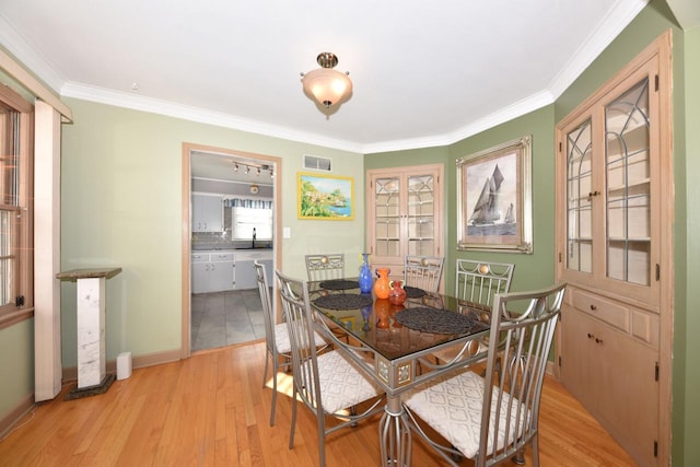 dining room featuring ornamental molding, sink, and light hardwood / wood-style flooring