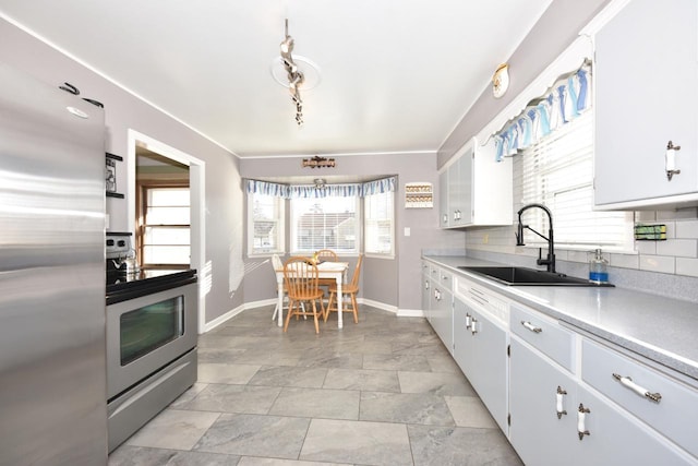 kitchen featuring stainless steel appliances, sink, white cabinets, and decorative backsplash