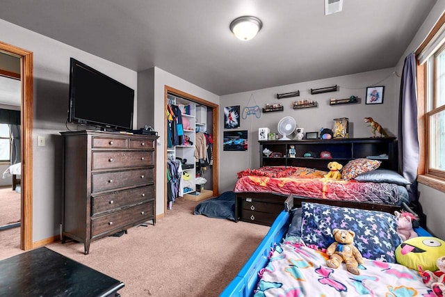 bedroom featuring multiple windows, light colored carpet, and a closet