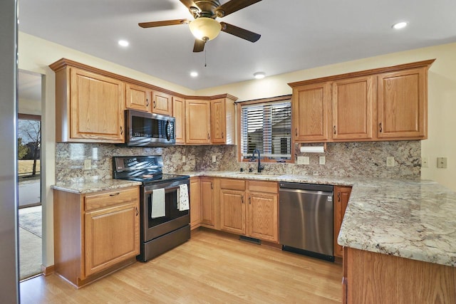 kitchen with tasteful backsplash, appliances with stainless steel finishes, sink, and light hardwood / wood-style floors