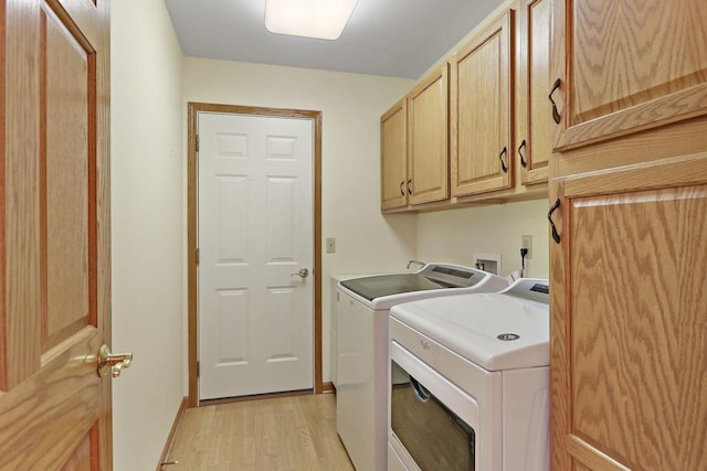 washroom with cabinets, washer and dryer, and light hardwood / wood-style flooring