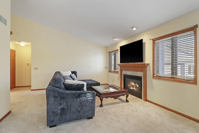 carpeted living room with vaulted ceiling and a tile fireplace