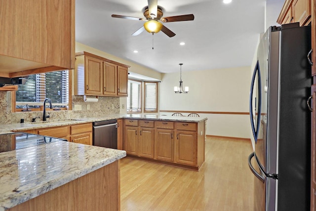 kitchen featuring light hardwood / wood-style flooring, stainless steel appliances, tasteful backsplash, decorative light fixtures, and kitchen peninsula