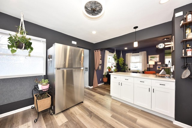 kitchen with pendant lighting, light hardwood / wood-style floors, stainless steel refrigerator, and white cabinets