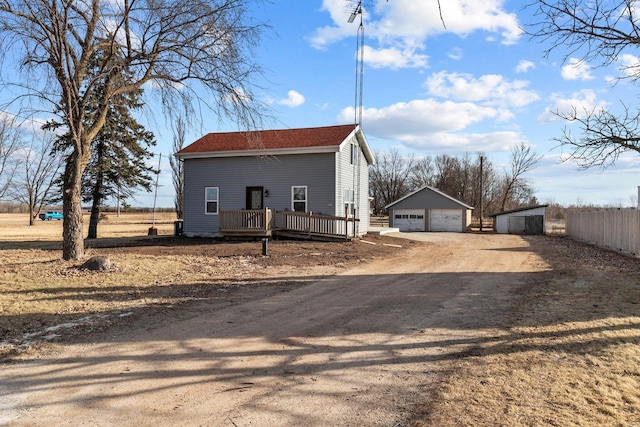 view of side of home featuring a garage, an outbuilding, and a deck