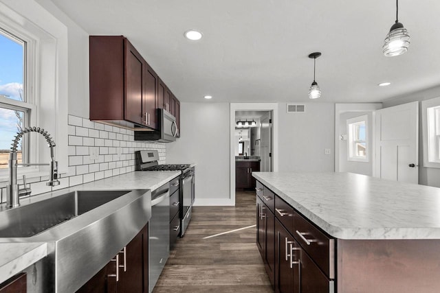 kitchen featuring stainless steel appliances, dark hardwood / wood-style floors, a center island, and hanging light fixtures