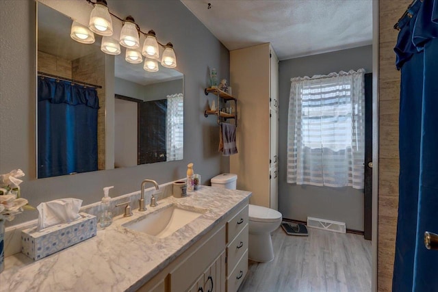 bathroom featuring wood-type flooring, vanity, walk in shower, toilet, and a textured ceiling