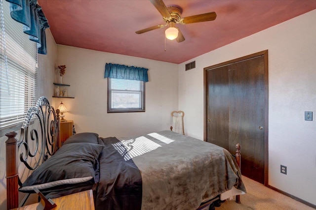 bedroom featuring multiple windows, carpet, ceiling fan, and a closet