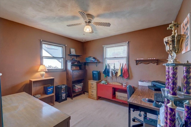 carpeted office featuring ceiling fan and a textured ceiling