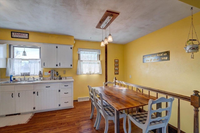 kitchen featuring hanging light fixtures, hardwood / wood-style flooring, sink, and white cabinets