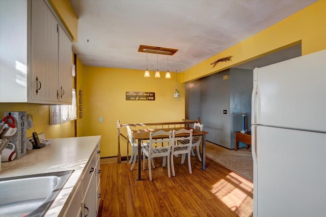 kitchen featuring sink, decorative light fixtures, light hardwood / wood-style floors, and white fridge