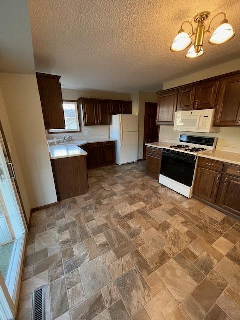 kitchen with white appliances, sink, dark brown cabinets, and a textured ceiling