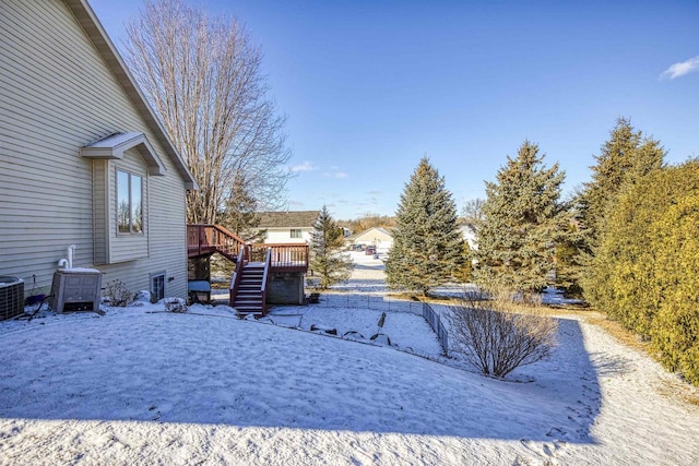 yard layered in snow featuring central AC unit and a deck