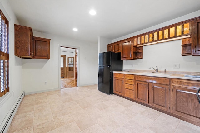 kitchen featuring black fridge, a baseboard heating unit, and sink