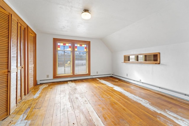 additional living space with lofted ceiling, light hardwood / wood-style floors, and a baseboard heating unit