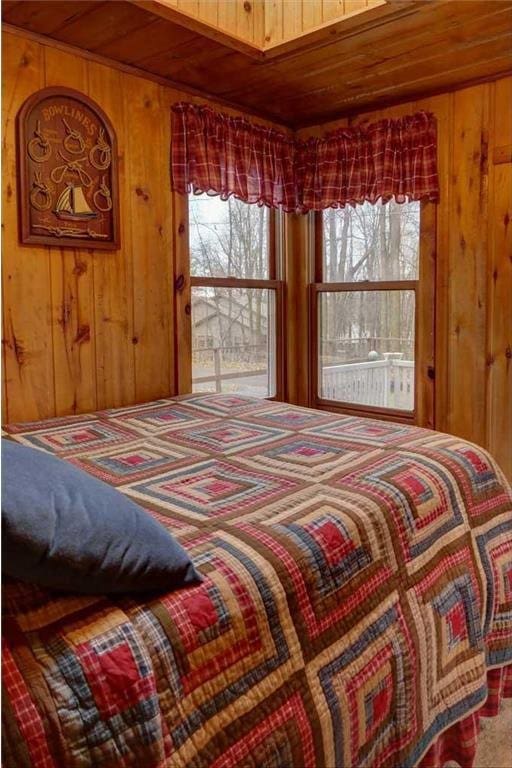 carpeted bedroom with wooden ceiling and wood walls