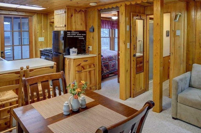 carpeted dining area with wooden walls and wood ceiling