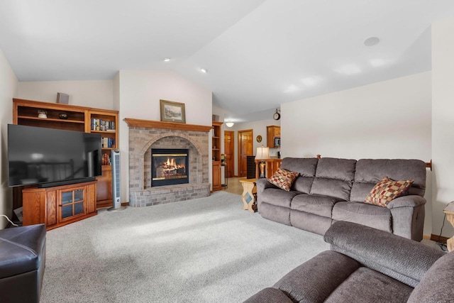 living room with vaulted ceiling, a brick fireplace, and carpet floors