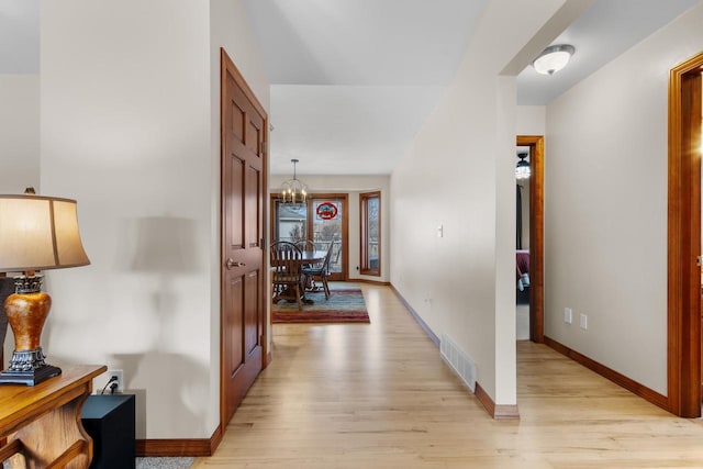 hallway with a chandelier and light wood-type flooring