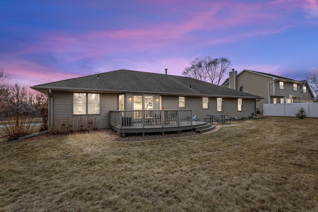 back house at dusk featuring a yard and a deck