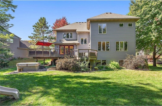 rear view of property featuring a yard, a hot tub, and a deck