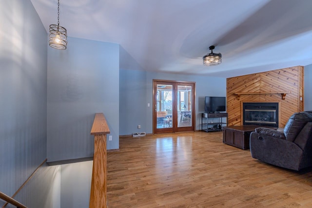 living room with light hardwood / wood-style floors, a fireplace, and wood walls