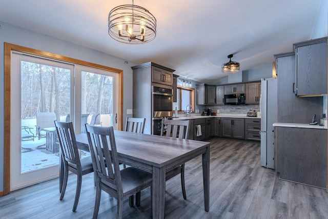 dining room featuring a chandelier, sink, light hardwood / wood-style floors, and vaulted ceiling