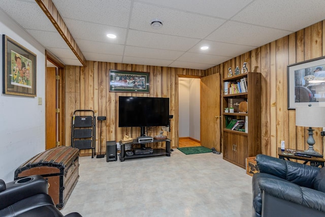 living room with a paneled ceiling and wooden walls