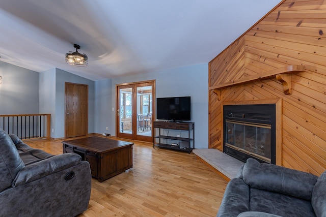 living room with lofted ceiling, light hardwood / wood-style floors, and wood walls