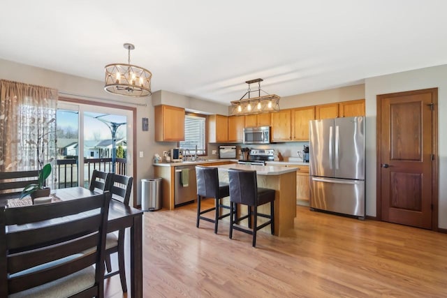 kitchen with hanging light fixtures, light hardwood / wood-style flooring, stainless steel appliances, and a center island